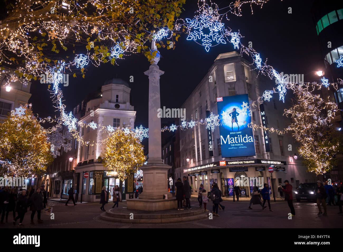 Scenic nighttime view of twinkling Christmas lights strung through trees surrounding the historic Seven Dials monument in London, England, UK Stock Photo