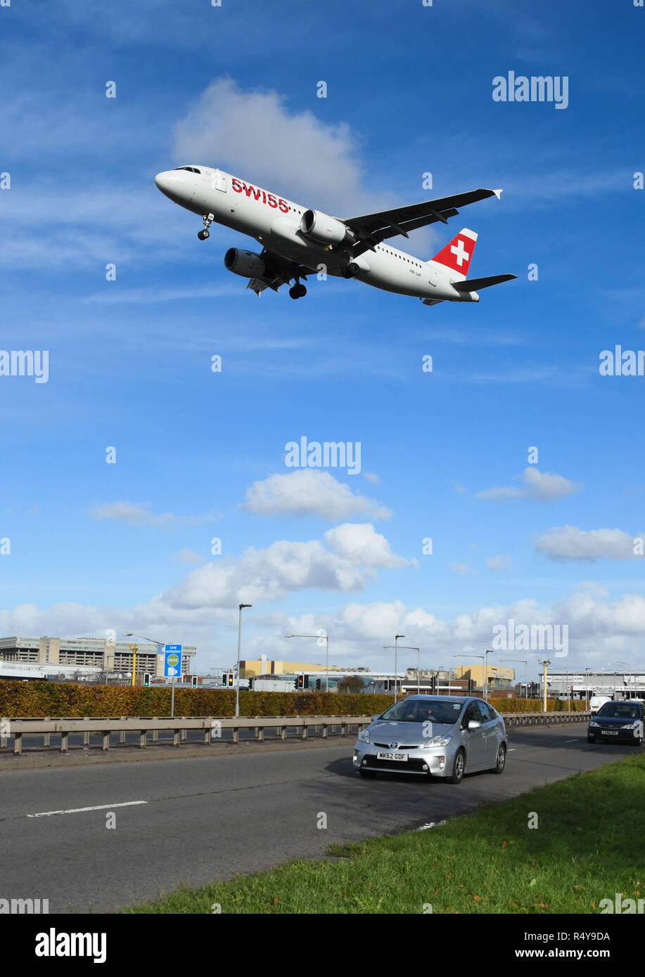 LONDON, ENGLAND - NOVEMBER 2018: Swiss airliner coming into land at London Heathrow Airport passing over traffic on the A30 dual carriageway. Stock Photo