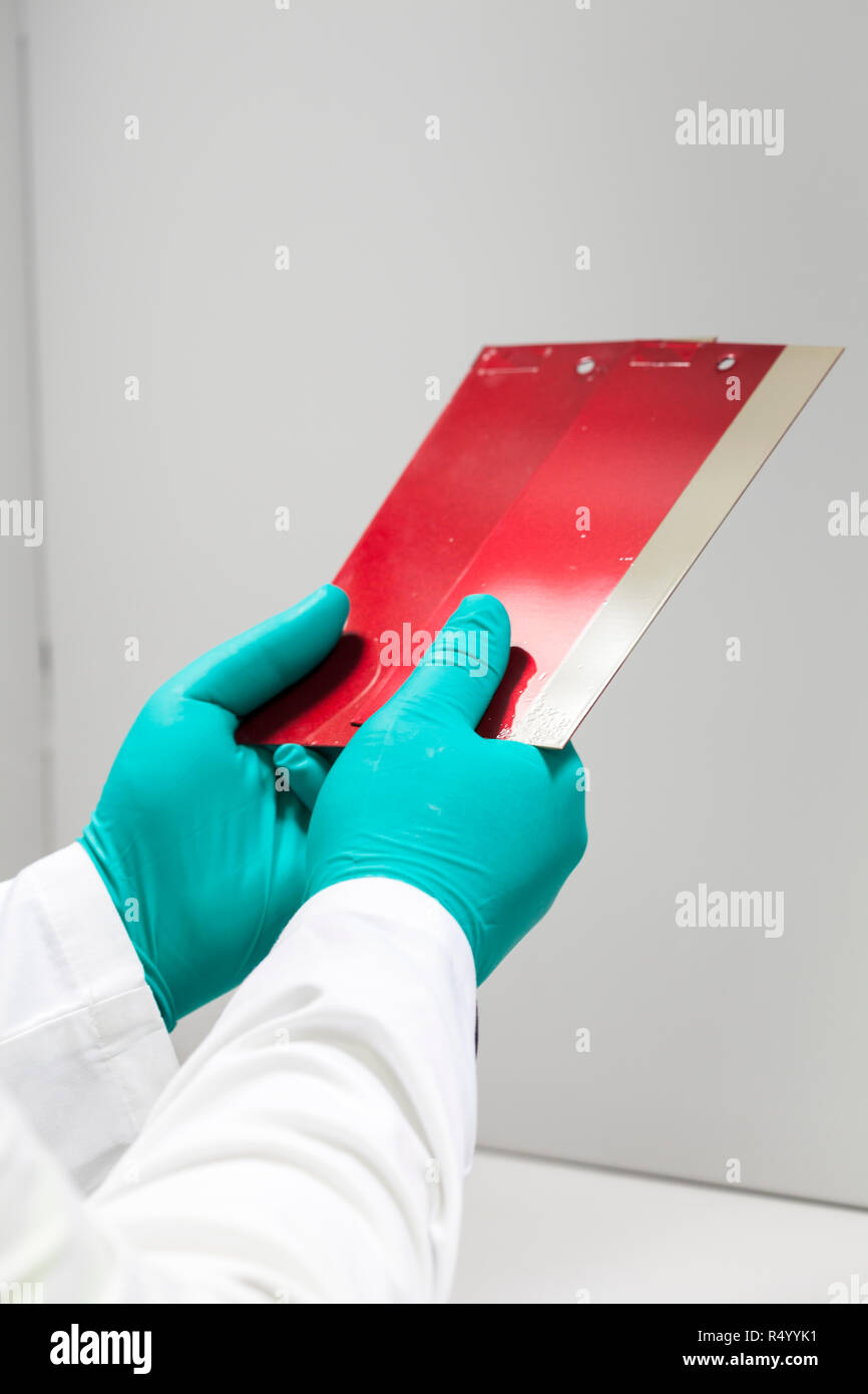 Laboratory technician checking and matching red paint in a color booth