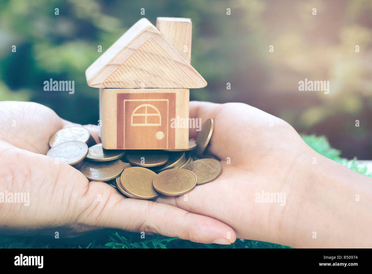 House placed on coins Men's hand is planning savings money of coins to buy a home concept concept for property ladder, mortgage and real estate invest Stock Photo
