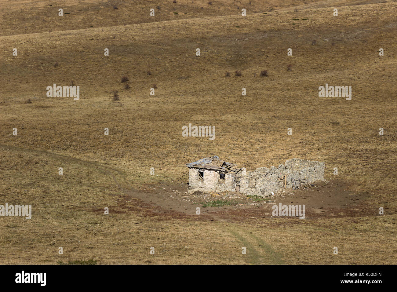 Sad, ruined, abandoned animal farm on the endless grassy highlands of Old mountain Stock Photo