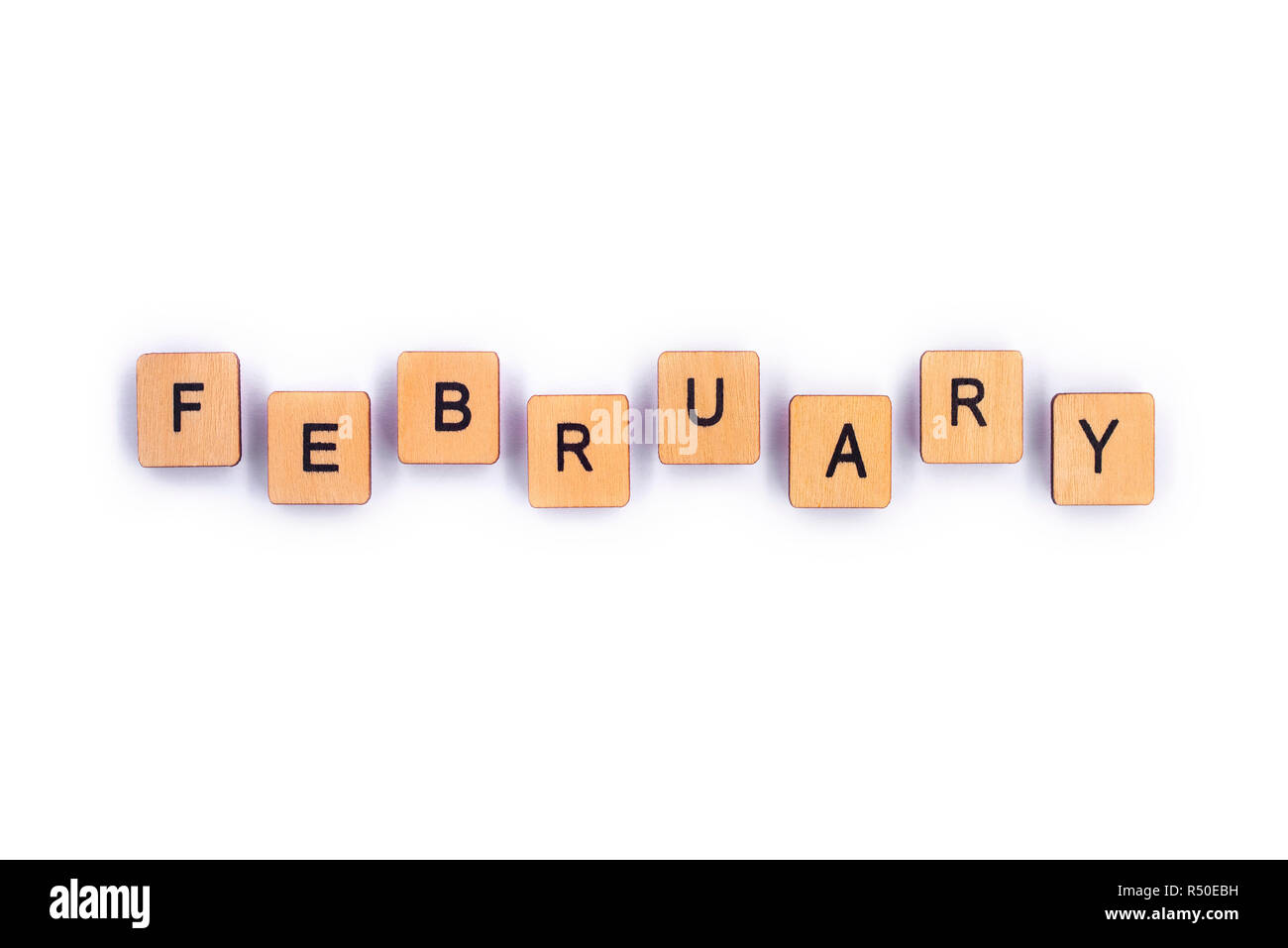 FEBRUARY, spelt with wooden letter tiles over a plain white background. Stock Photo