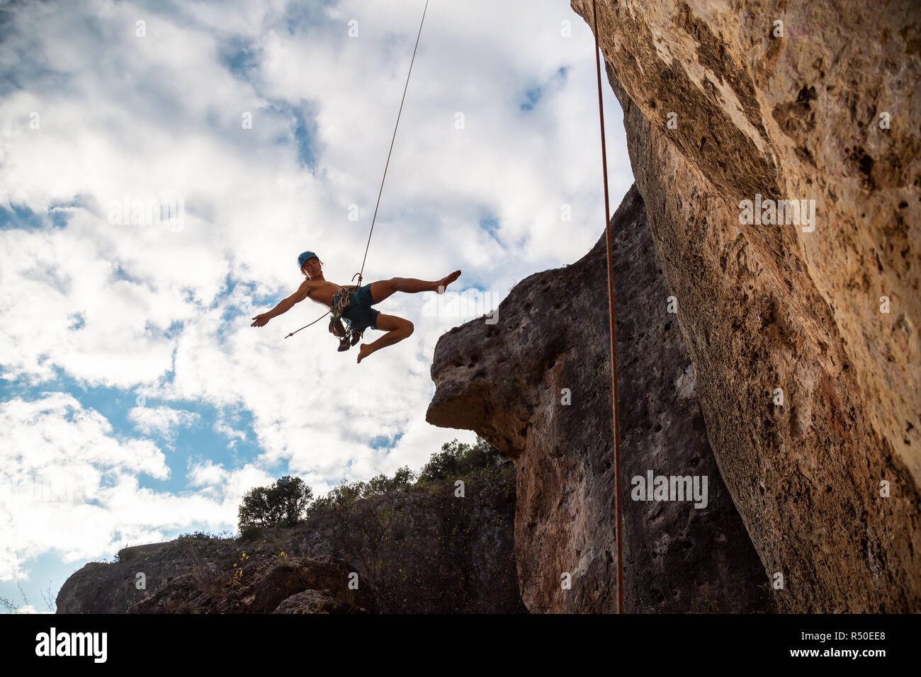 Man in hardhat hanging on rope while doing rappel and showing ...