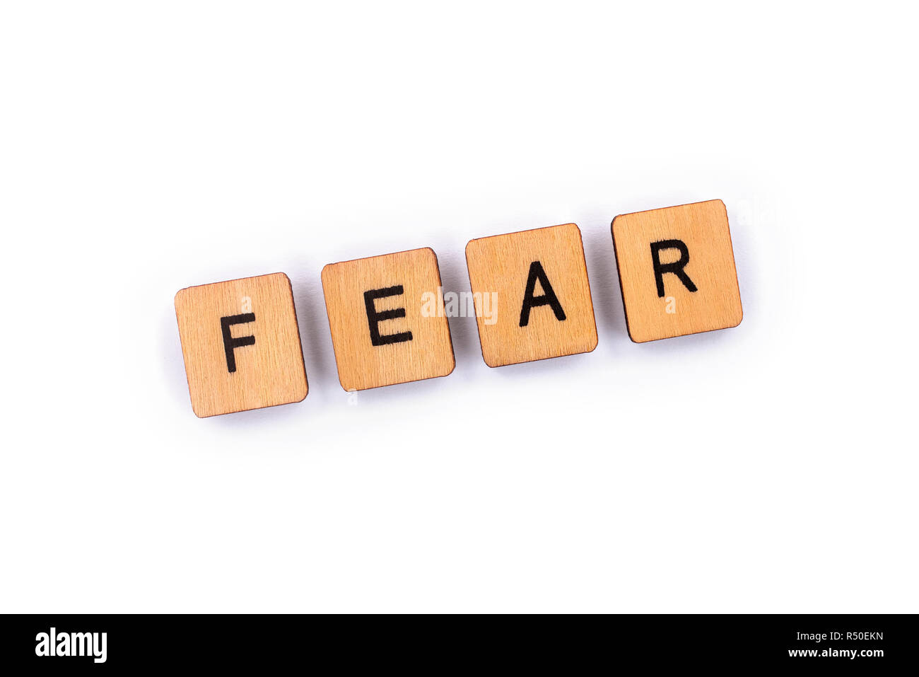 FEAR, spelt with wooden letter tiles over a plain white background. Stock Photo