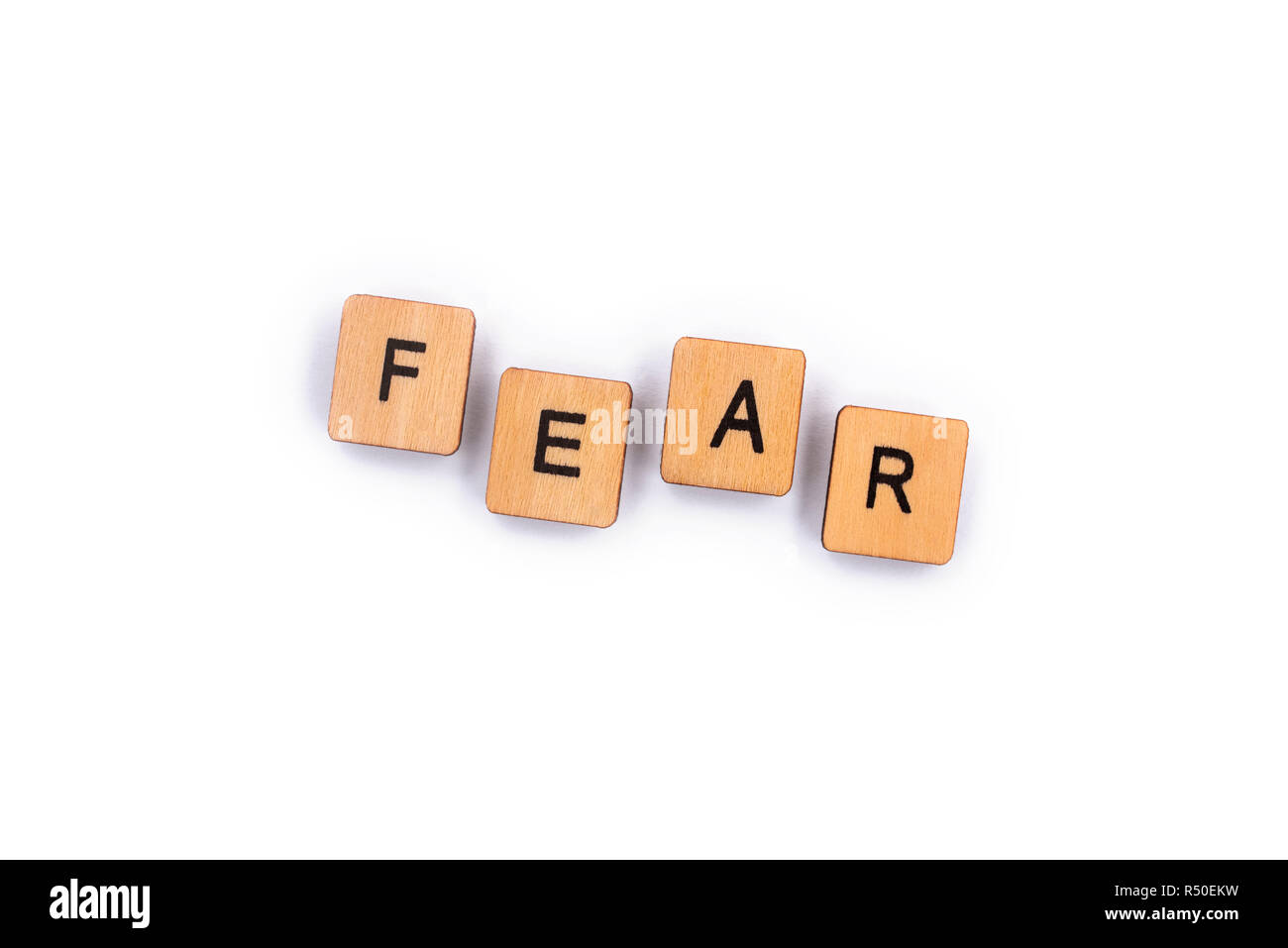 FEAR, spelt with wooden letter tiles over a plain white background. Stock Photo