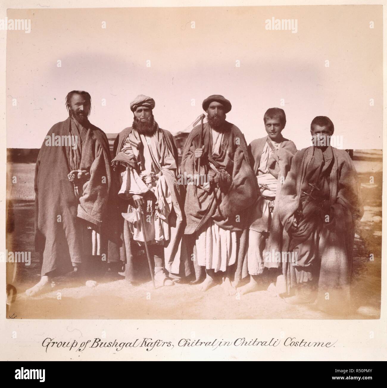 Group of Bushgal Kafirs, Chitral, in Chitrali costume. Sep-Nov 1885.  The Mission was at Chitral from 11-18 September 1885 and again from early October to mid-November. [Albumen print, 244x202mm]. Album of 'Photographs, Gilgit, Chitral, Yassin, Mastuch, &ca.' [Gilgit Mission]. The photographs are recorded as having been sent from India to the Secretary of State in August 1886., August 1886,. Source: Photo 1040/70. Author: Giles, George Michael James. Stock Photo