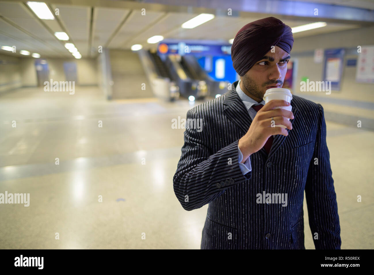 Indian Sikh businessman at subway train station drinking coffee Stock Photo