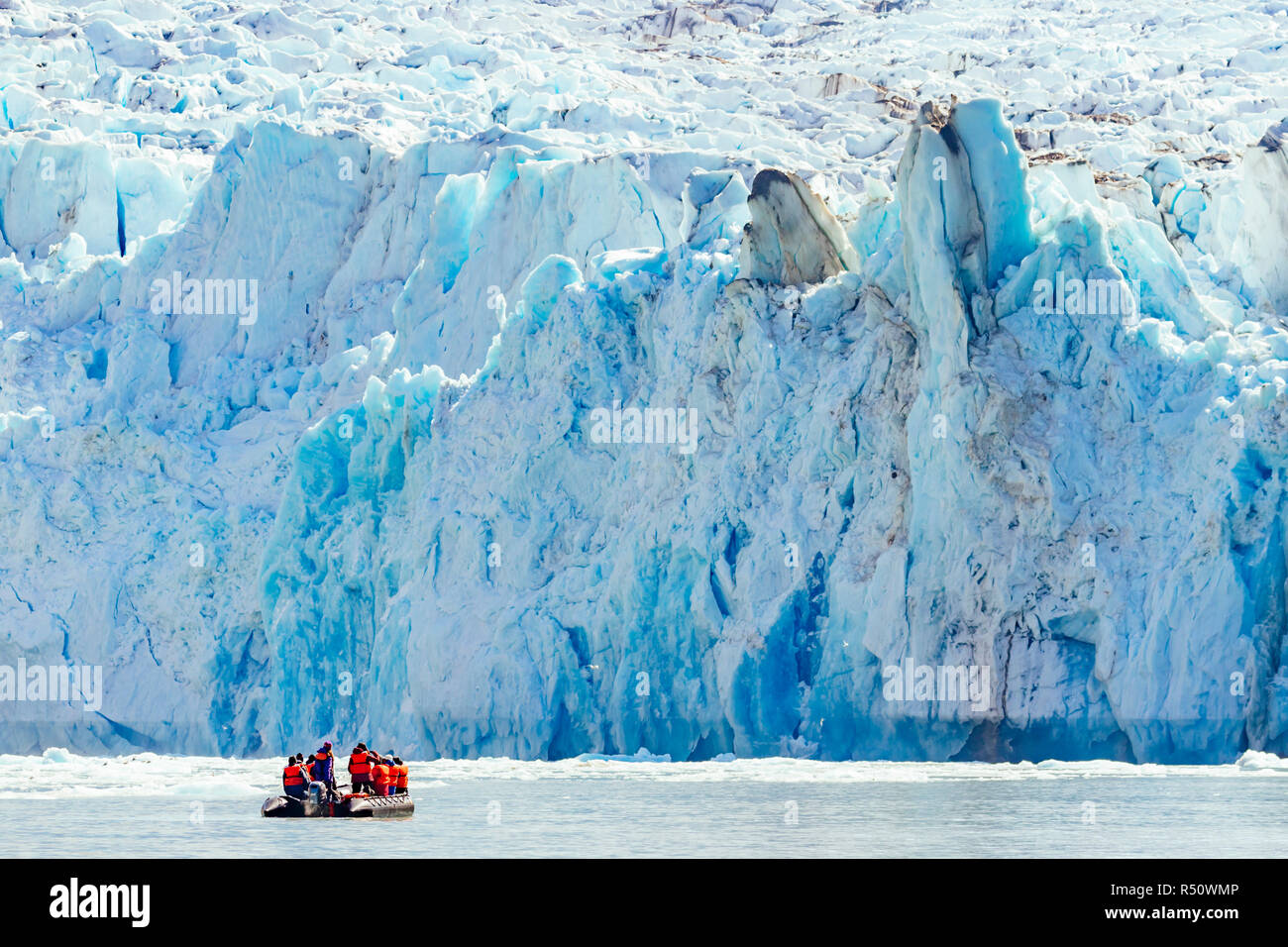 A group of expedition ship passengers are exploring the glacial face of Dawes Glacier in Endicott arm fjord in southeast Alaska, USA Stock Photo
