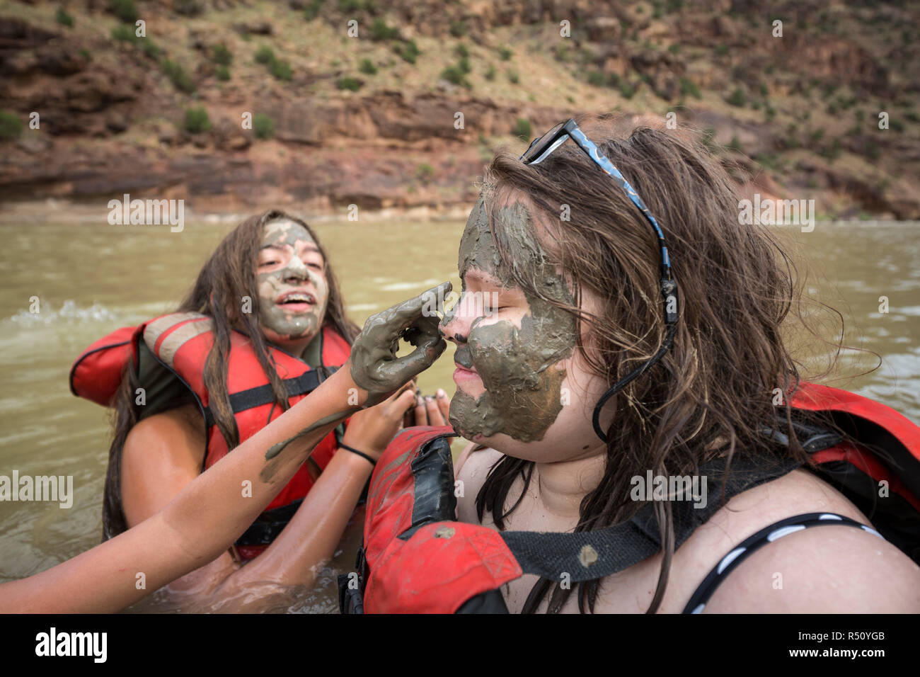 Two children playing in the river and painting mud on each others faces while on a Green river rafting trip, Desolation/Gray Canyon section, Utah, USA Stock Photo