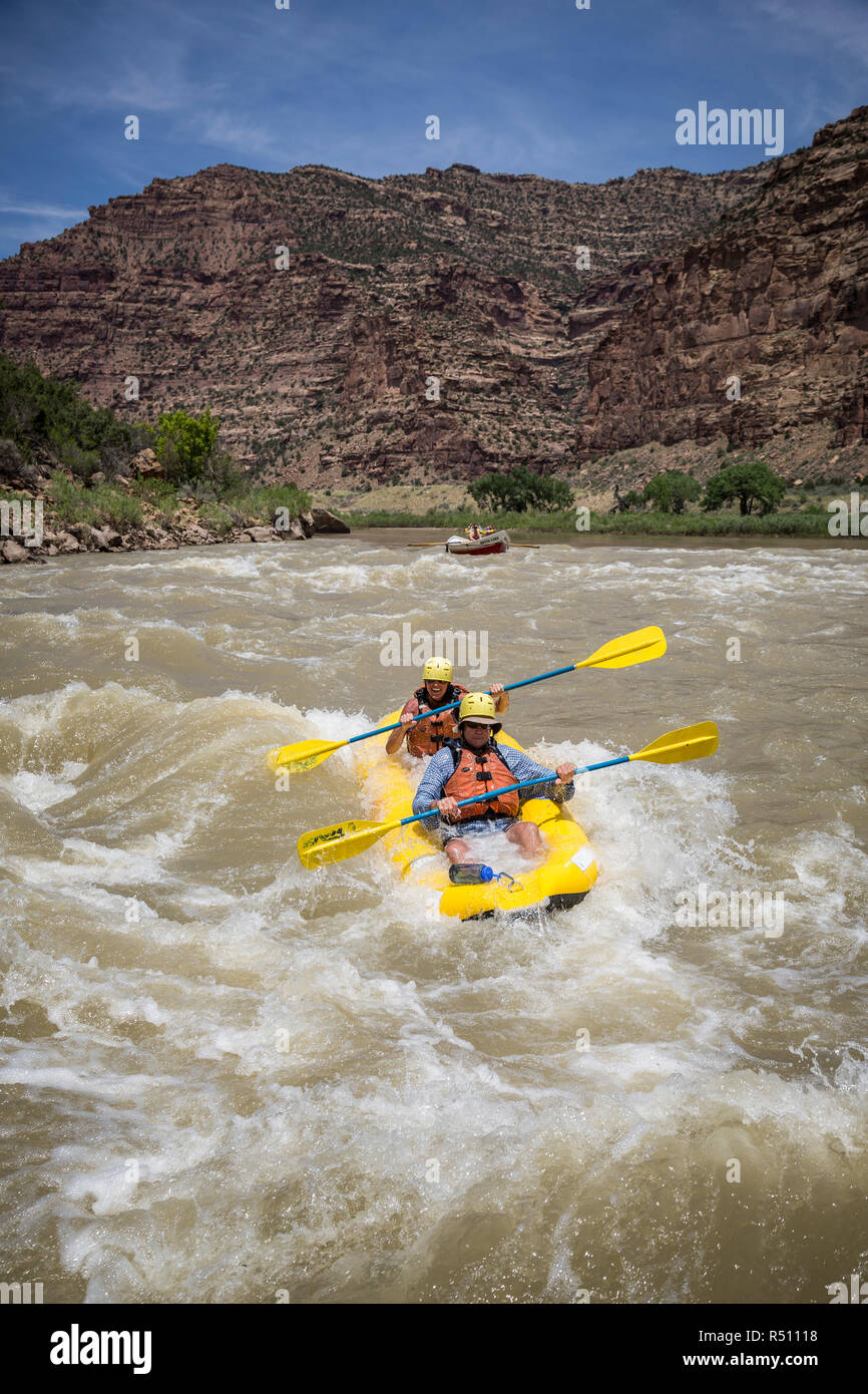 A man and woman paddling an inflatable kayak through rapids on a Green river rafting trip, Desolation/Gray Canyon section, Utah, USA Stock Photo