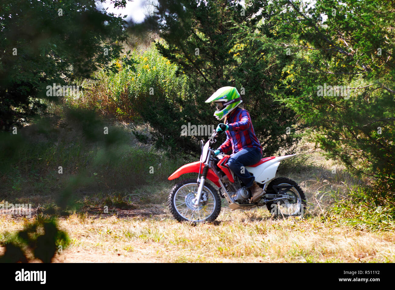 Side view shot of a single boy riding a motorcycle in a forest Stock Photo