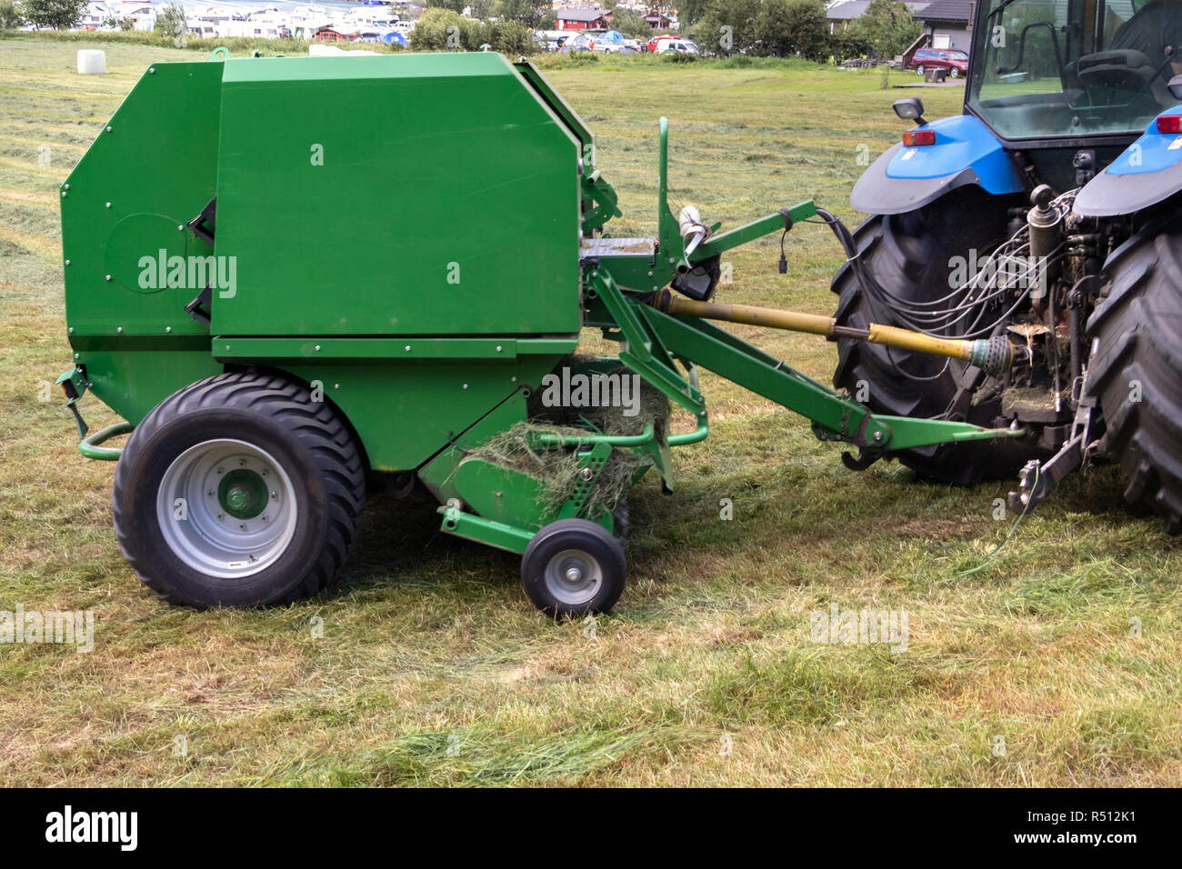 Closeup of a round baler attached to a tractor on a field in Geiranger, Norway. Stock Photo