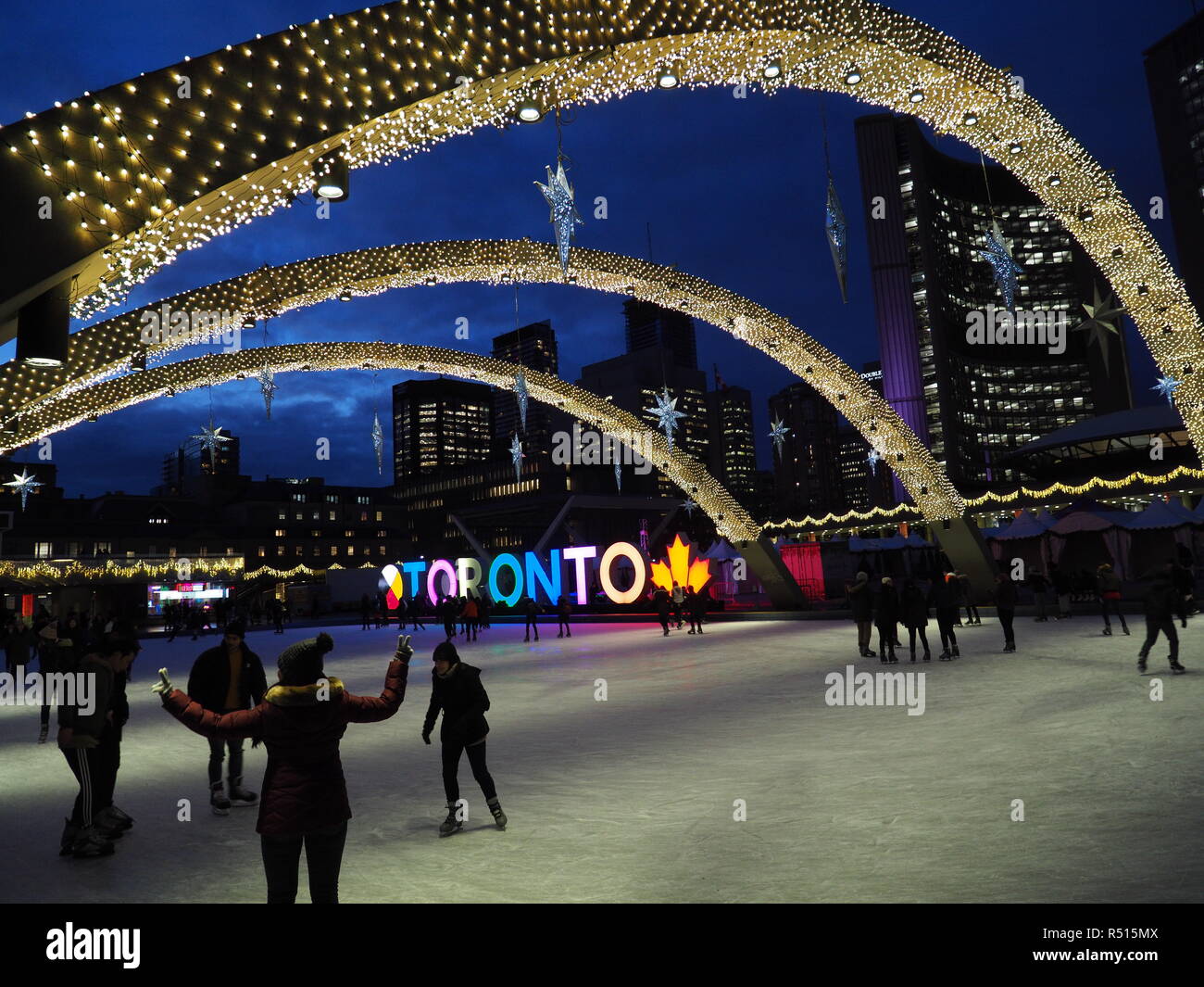 Skating rink with Christmas lights and lit Toronto sign, evening in front of Toronto's modern City Hall Stock Photo