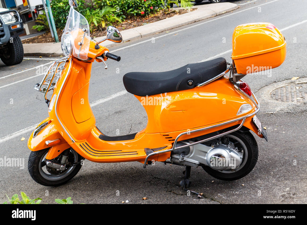 Bright orange coloured scooter parked on street Stock Photo