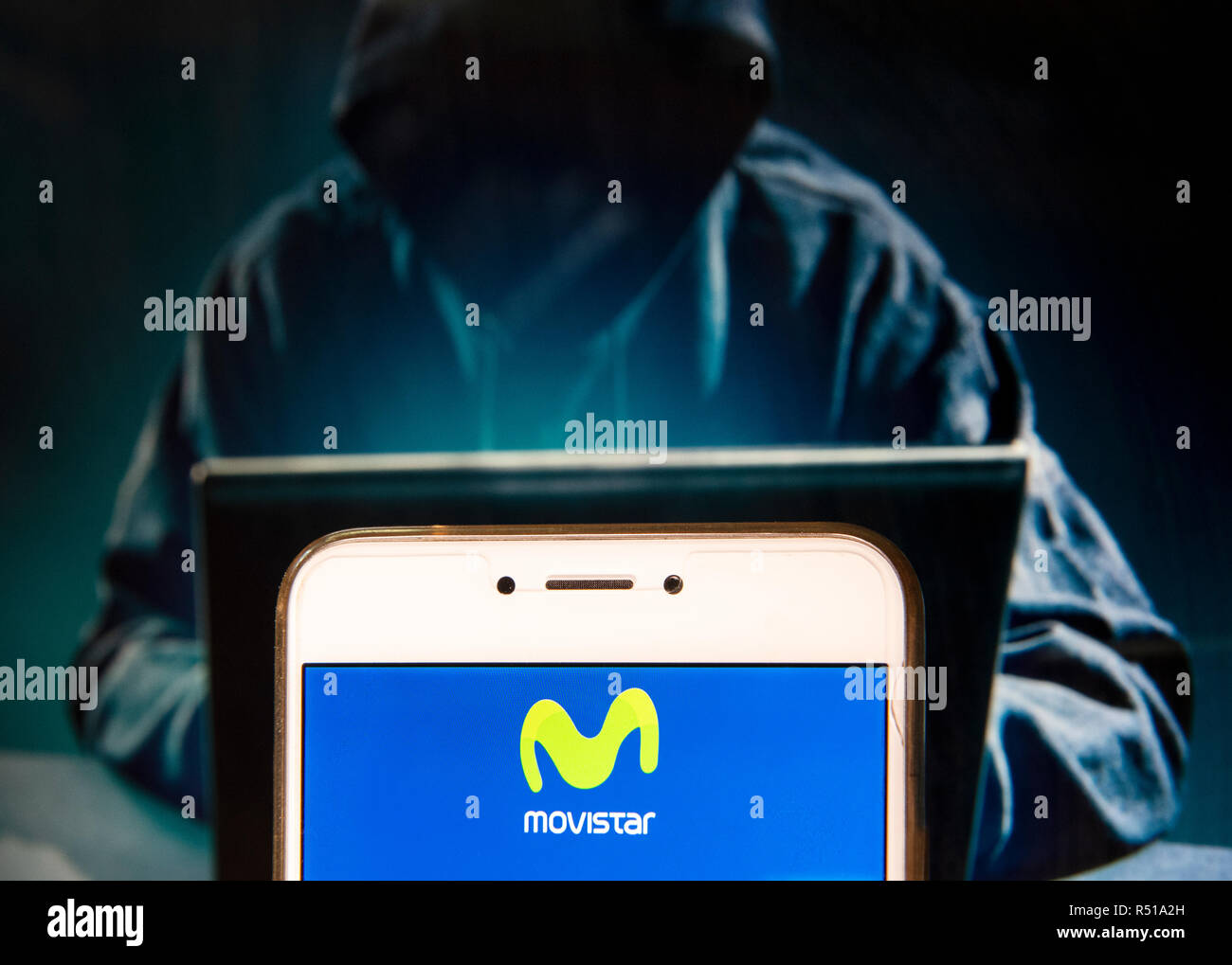 Spanish telecommunications brand owned by Telefonica and largest mobile phone operator, Movistar, logo is seen on an Android mobile device with a figure of hacker in the background. Stock Photo