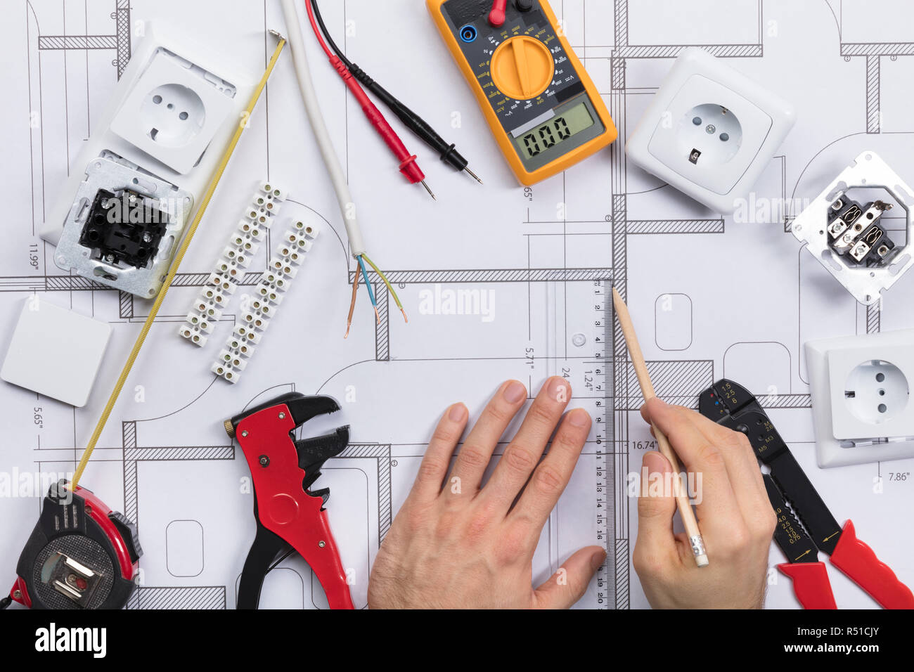 Architect Drawing Plan On Blueprint With Electrical Components Stock Photo