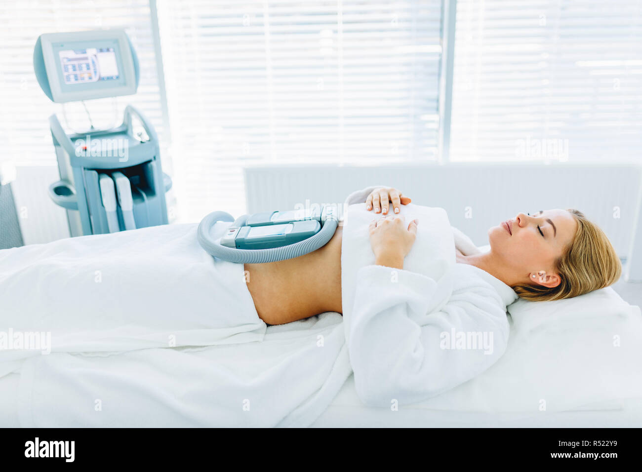 Young woman lying in medical couch with cooling elements on belly in clinic Stock Photo