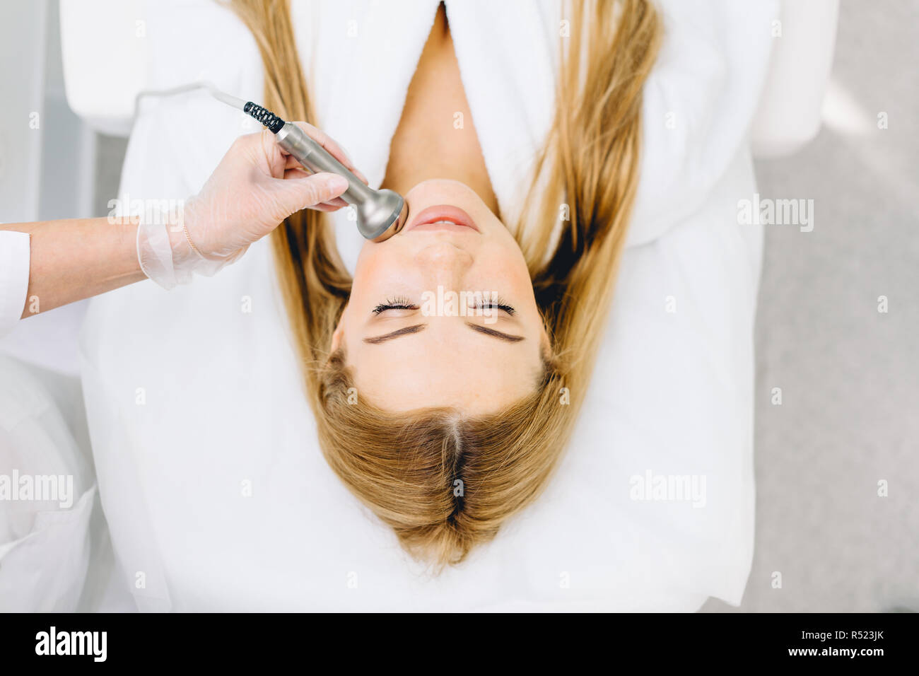 Blonde woman has ultrasonic dinamic lift massage in spa, hardware apparatus. Stock Photo