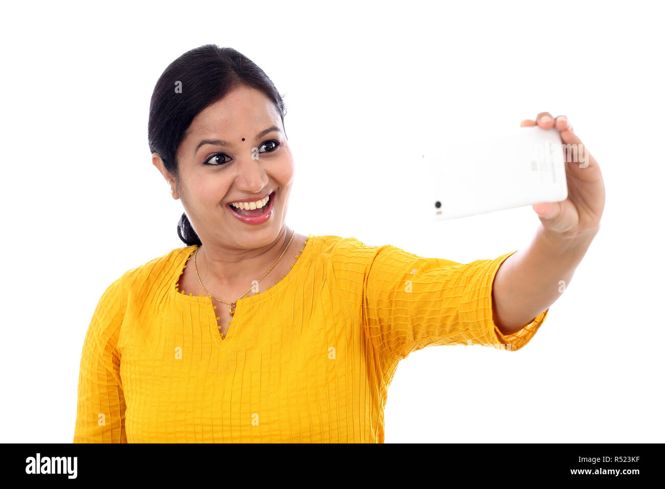 Happy young woman taking a selfie against white background Stock Photo ...