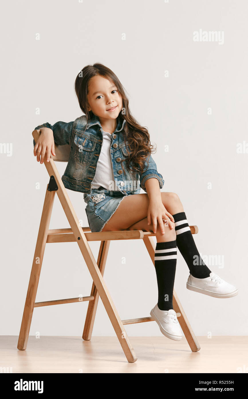 Full length portrait of cute little kid girl in stylish jeans clothes  looking at camera and smiling against white studio wall. Kids fashion  concept Stock Photo - Alamy