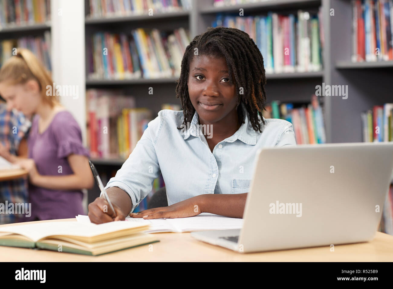 Portrait Of Female High School Student Working At Laptop In Library Stock Photo