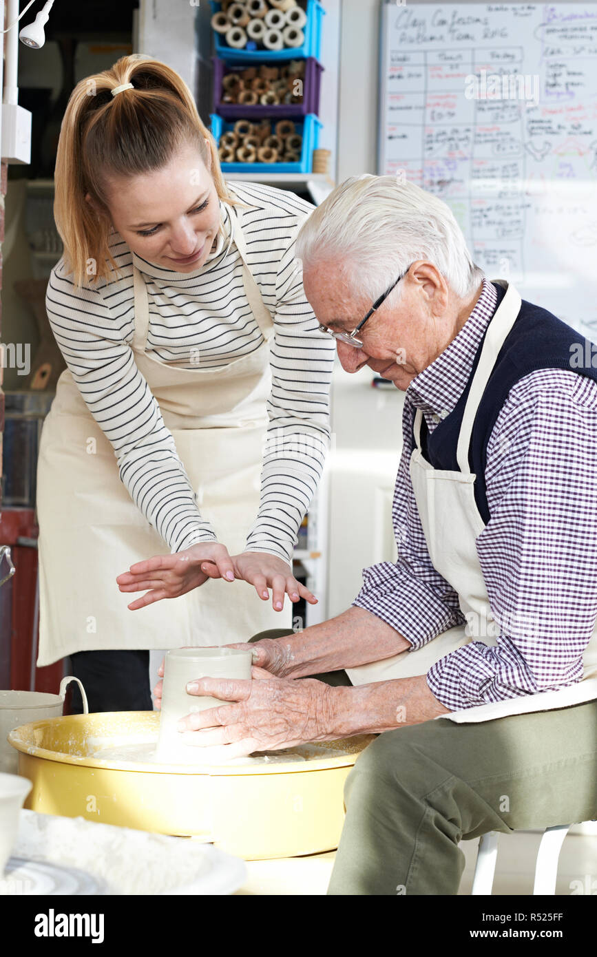 Senior Man With Teacher In Pottery Class Stock Photo