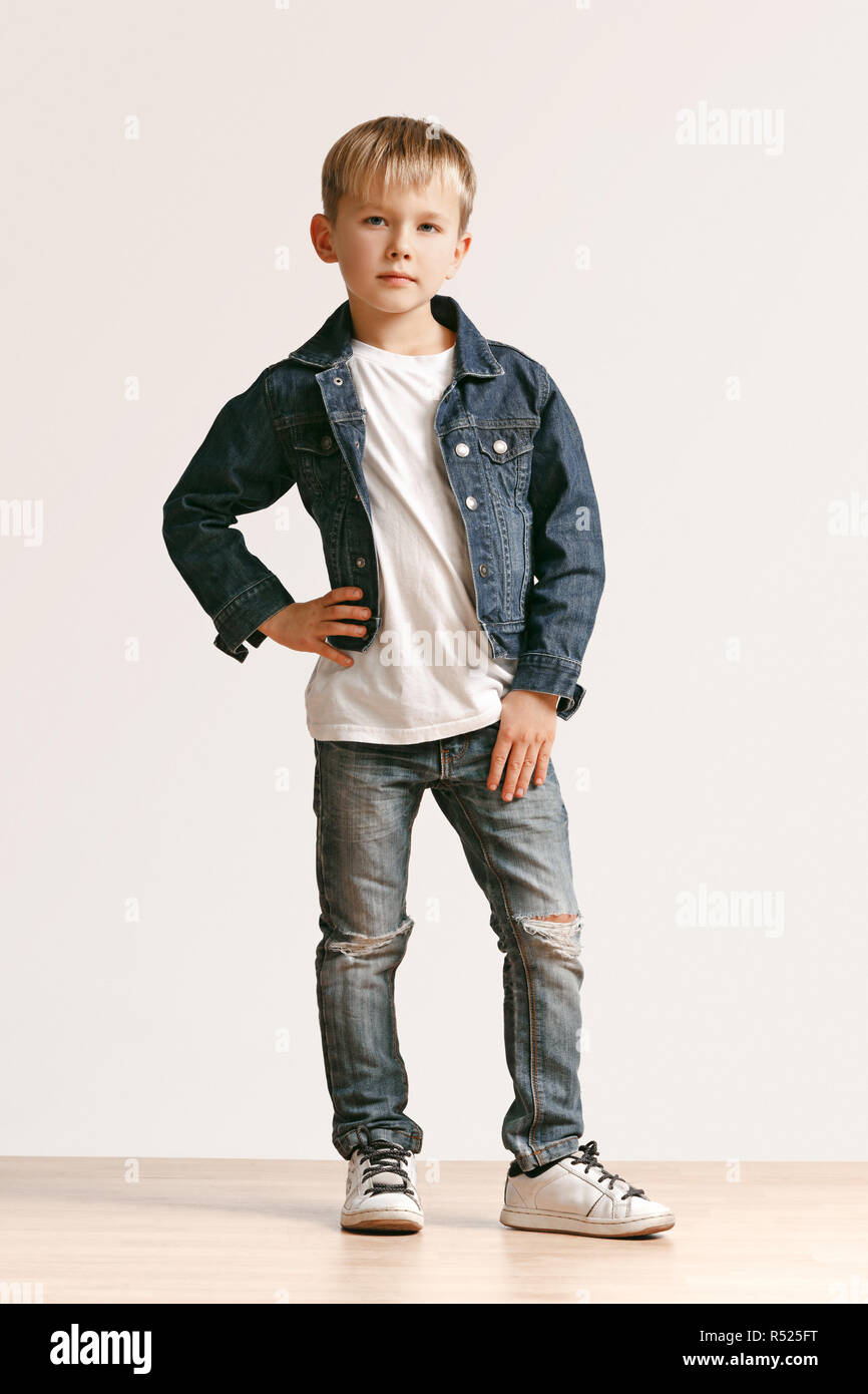 The portrait of cute little kid boy in stylish jeans clothes looking at camera  against white studio wall. Kids fashion concept Stock Photo - Alamy