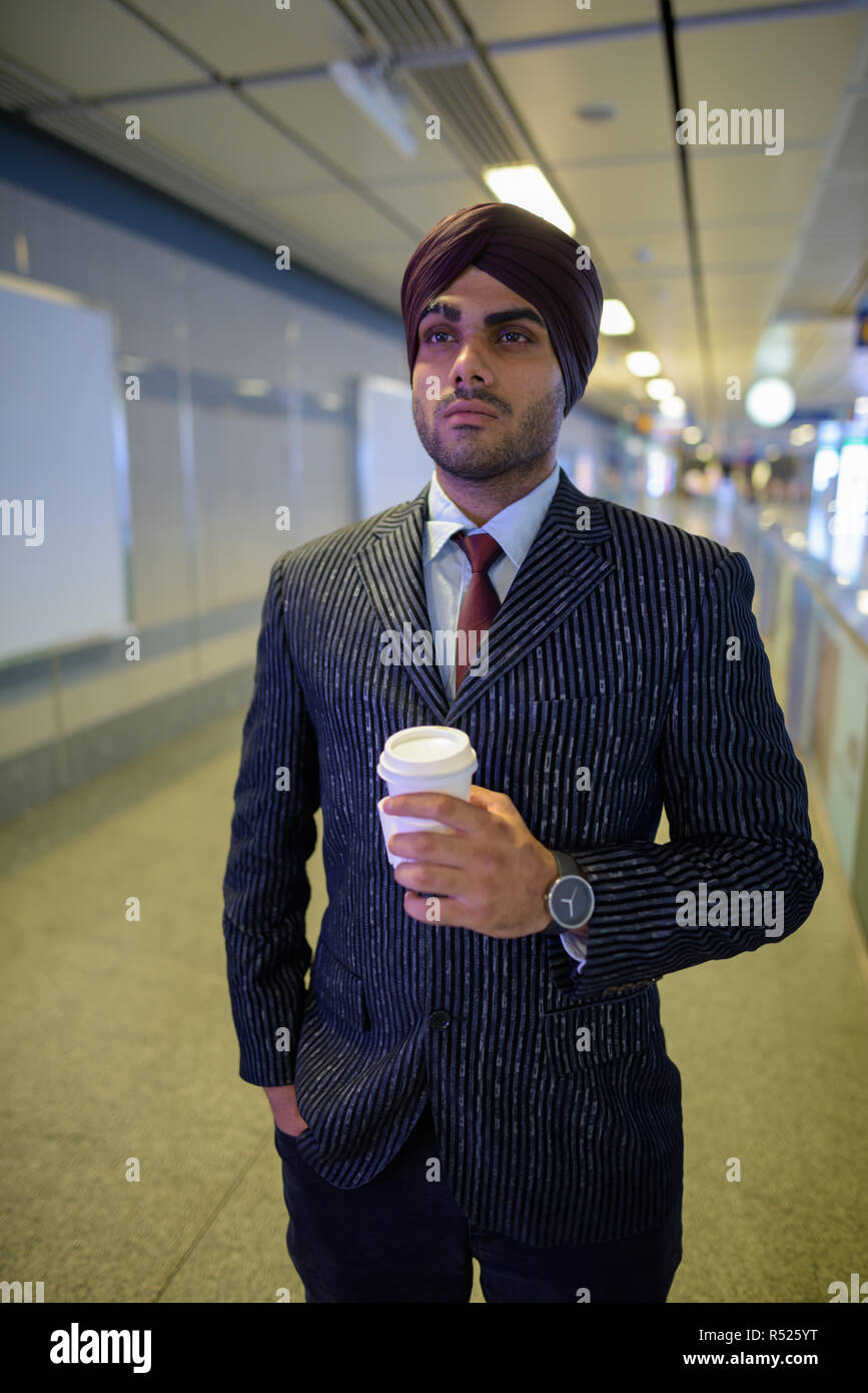 Indian Sikh businessman at subway train station holding coffee cup Stock Photo