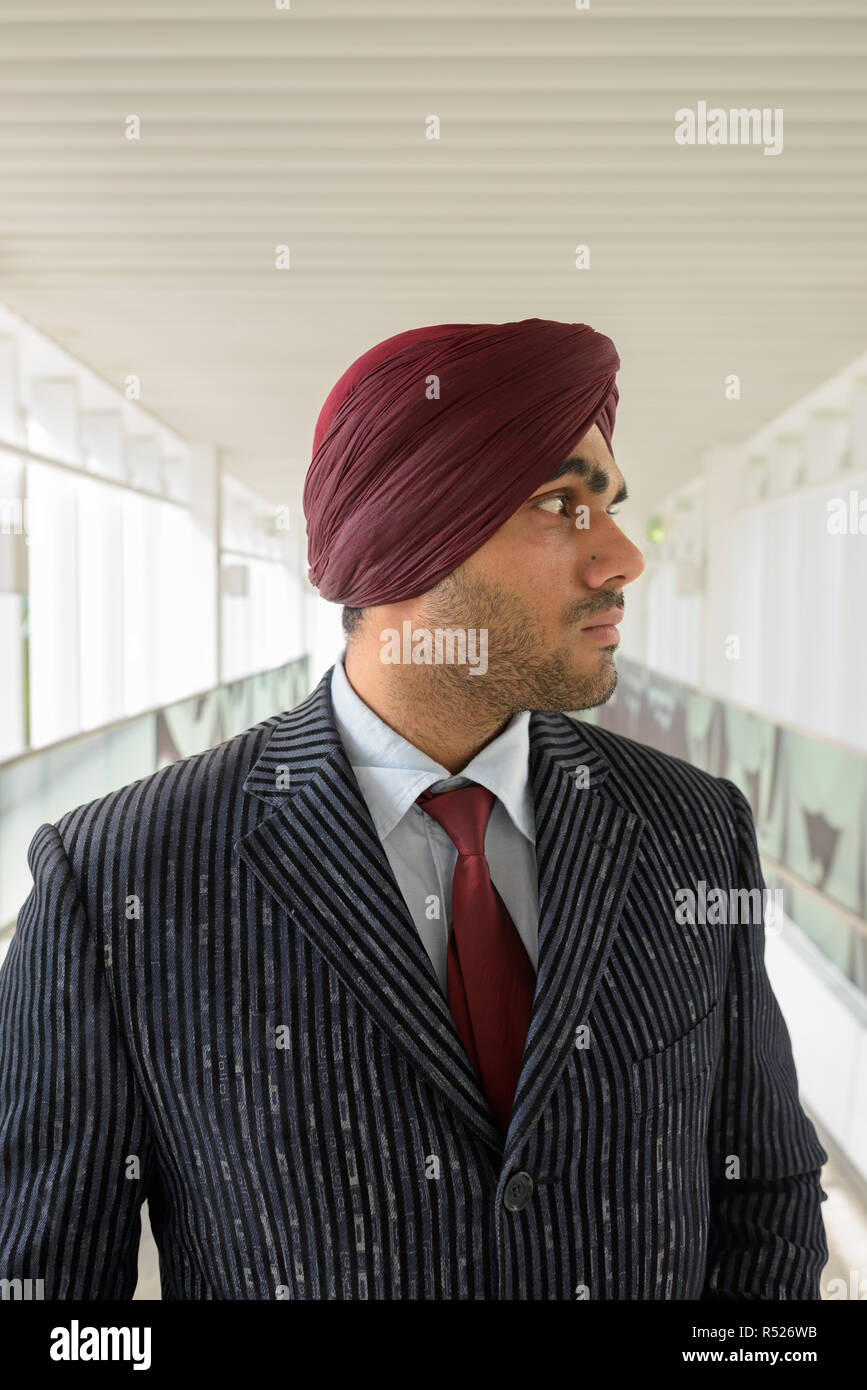 Portrait of Indian businessman with turban thinking outdoors in city Stock Photo