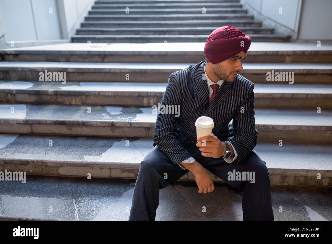 Portrait of Indian businessman sitting on stairs outdoors in city Stock Photo