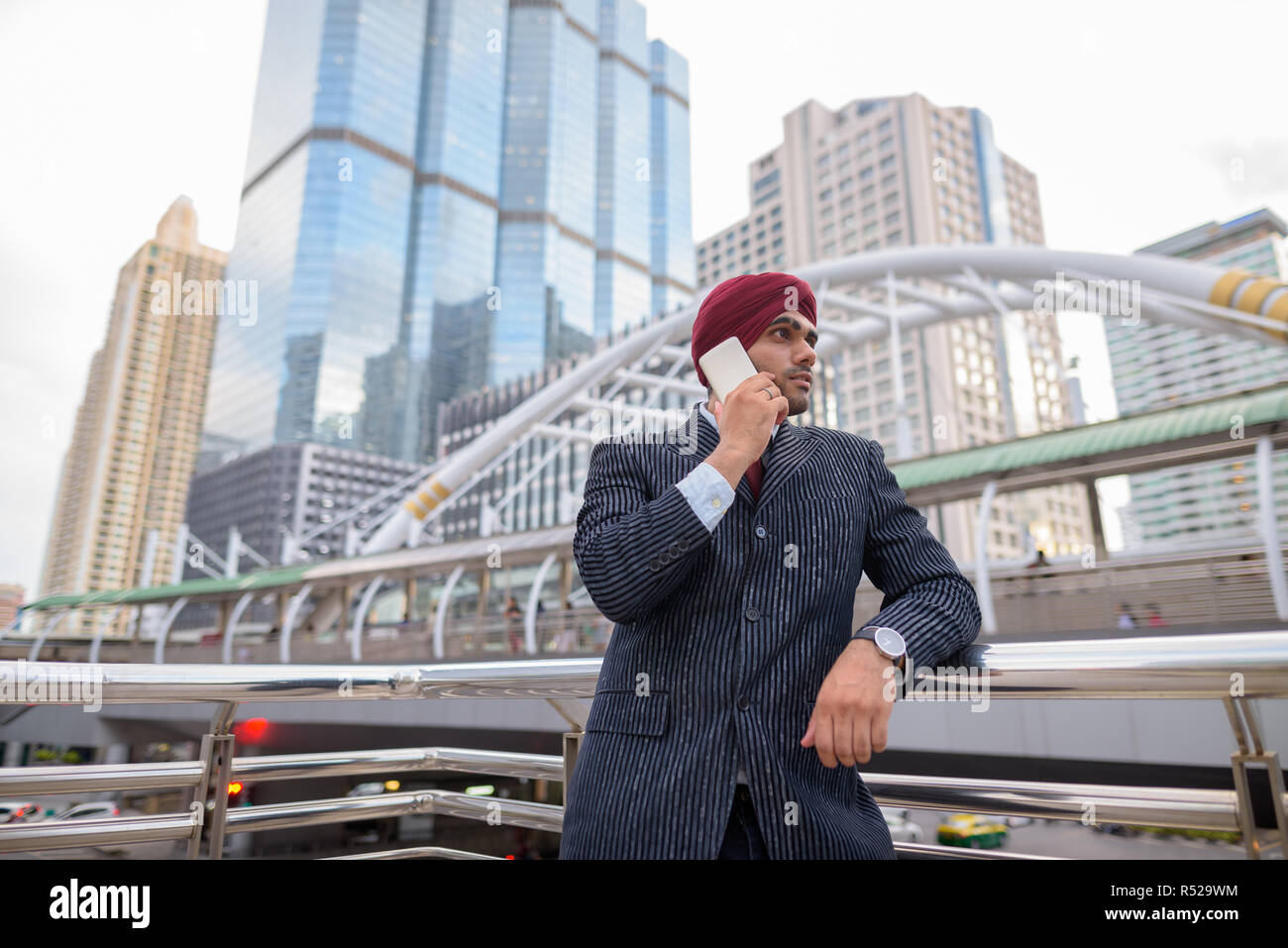 Indian businessman with turban outdoors in city using mobile phone Stock Photo