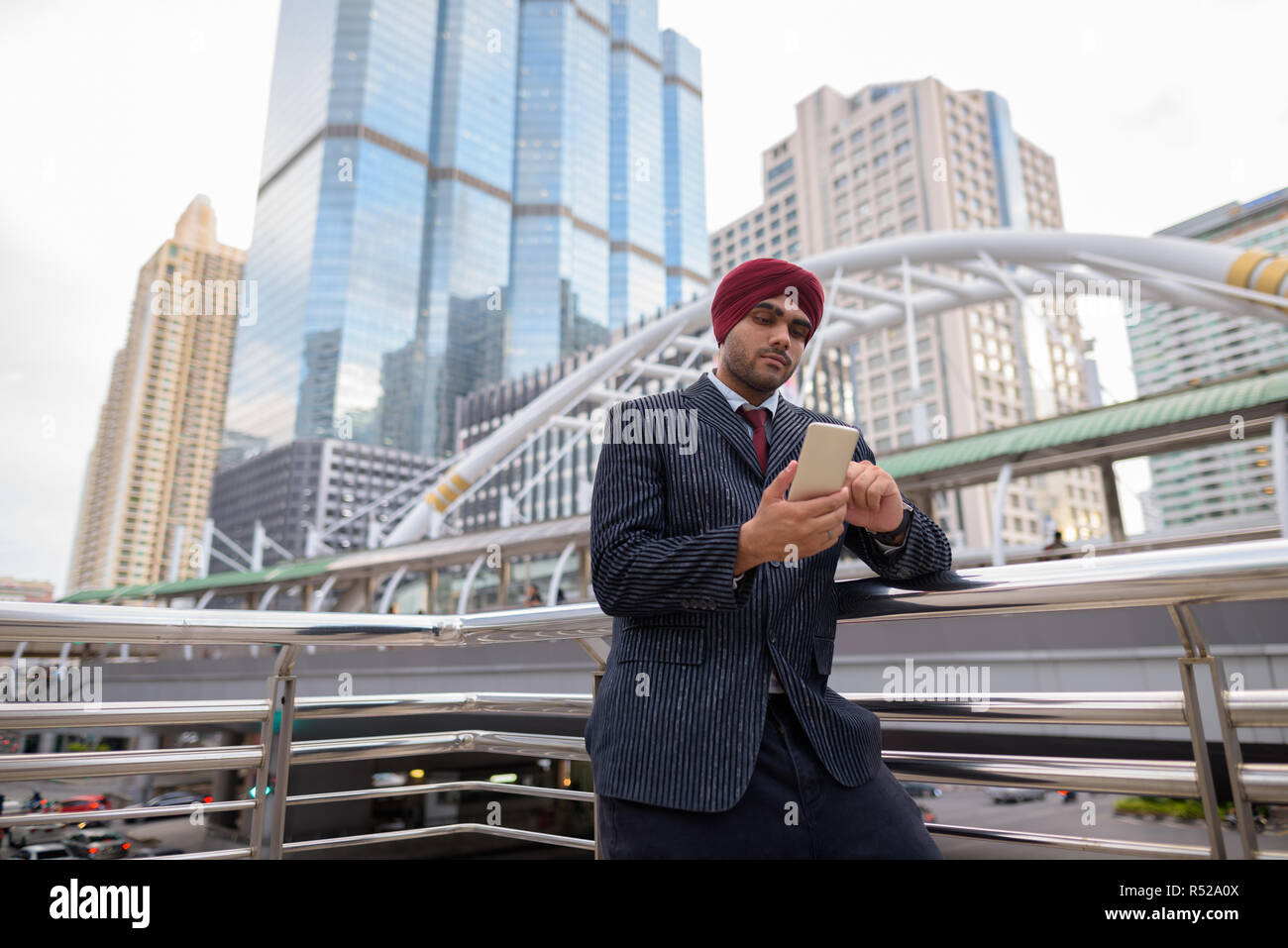 Indian businessman with turban outdoors in city using mobile phone Stock Photo
