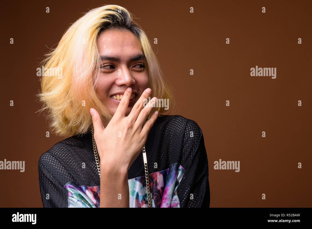 Young Asian man laughing and covering mouth Stock Photo