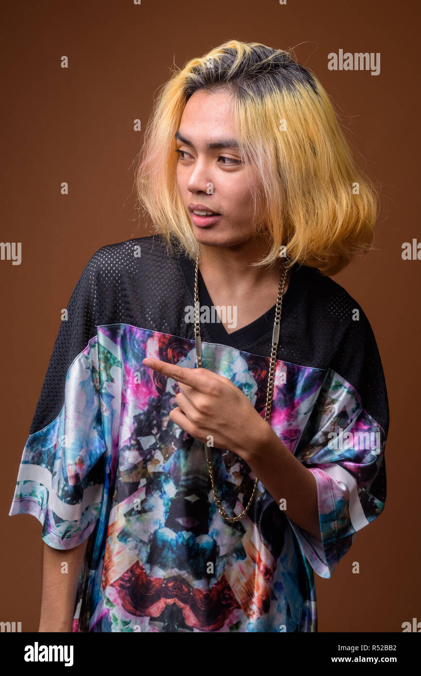 Young Asian man wearing stylish clothes against brown background Stock Photo