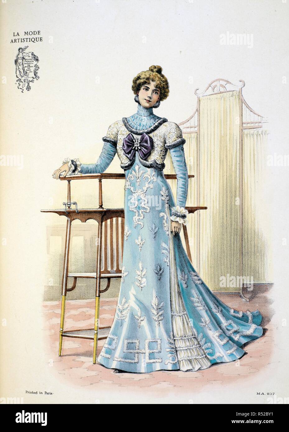 Design by Paquin. A tea-gown. Soft satin in turquoise blue is the material, embroidered with incrustations of mousseline bouillonneÃ© edged with white chenille in an Empire style. ... The gown is cut up on the left side to show a petticoat of gauged mousseline de soie, which soft material has also been used for the guimpe and sleeves. The bolero is made of guipure, in the Empre fashion, and is decorated with a large bow of bright parma-coolured velvet clasped by a buckle Ã  l'Empire. The cuffs have a band of fur and double frill of mousseline. The Powder Puff [An English edition of 'La Mode ar Stock Photo