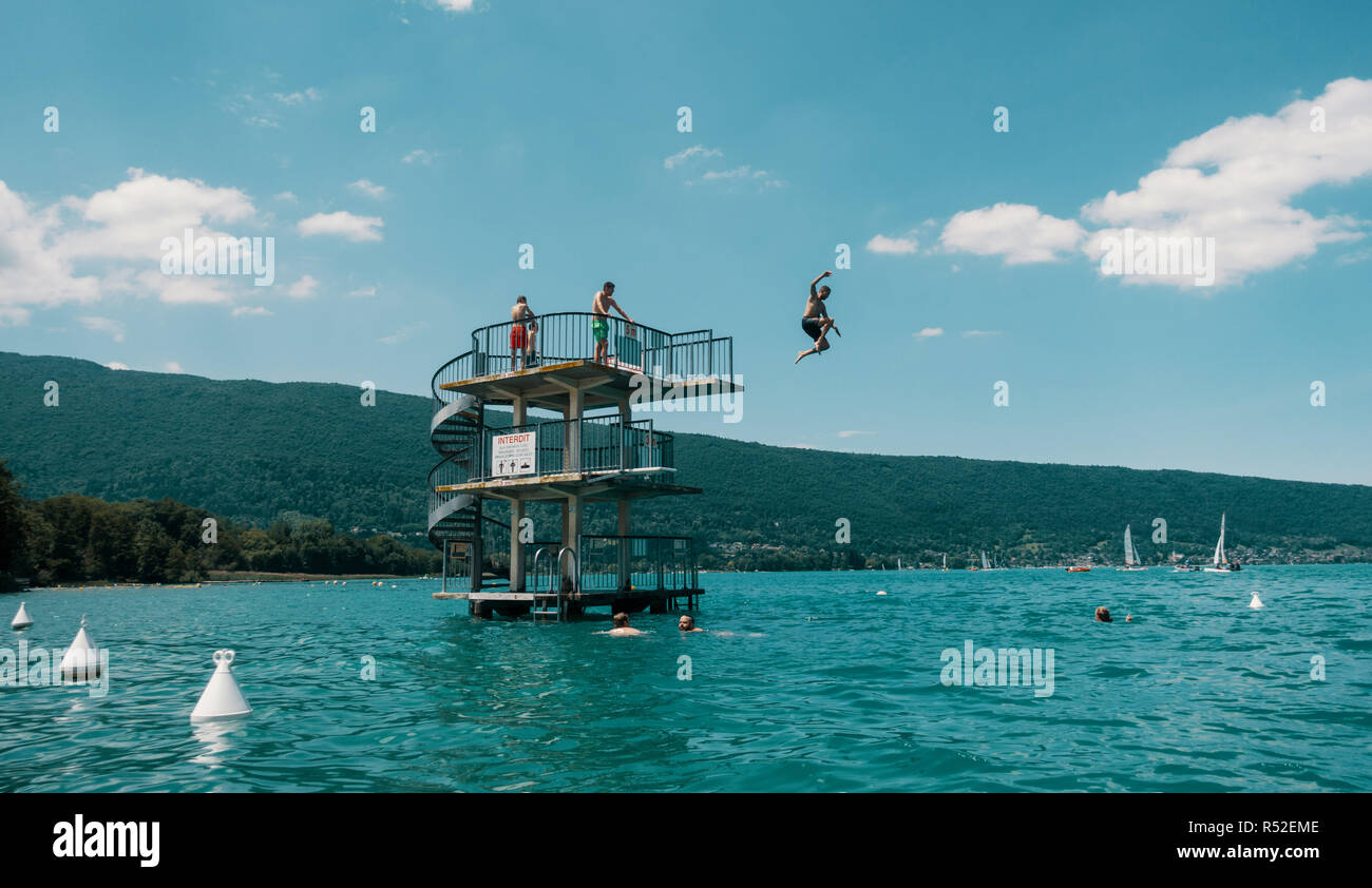 A swimmer jumps off a diving platform in the waters at Saint-Jorioz beach, Lake Annecy, in Annecy, France on June 15, 2018. Stock Photo
