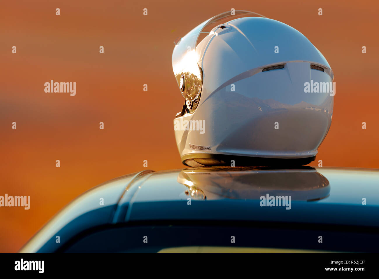 A Racing Helmet Sitting On Top Of A Car at the track In The Early Morning Sun Stock Photo