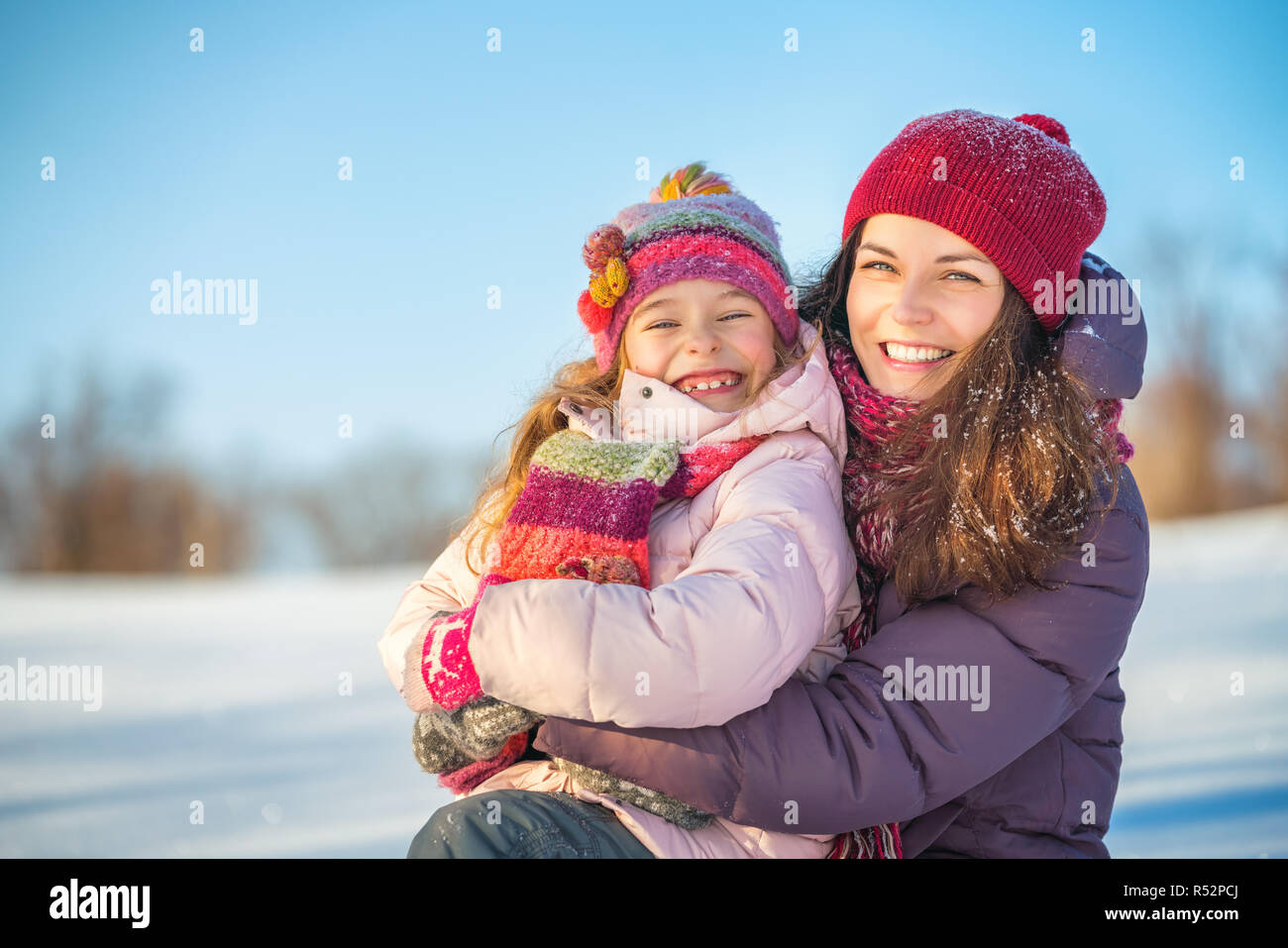 Little girl and her mother playing outdoors at sunny winter day Stock Photo