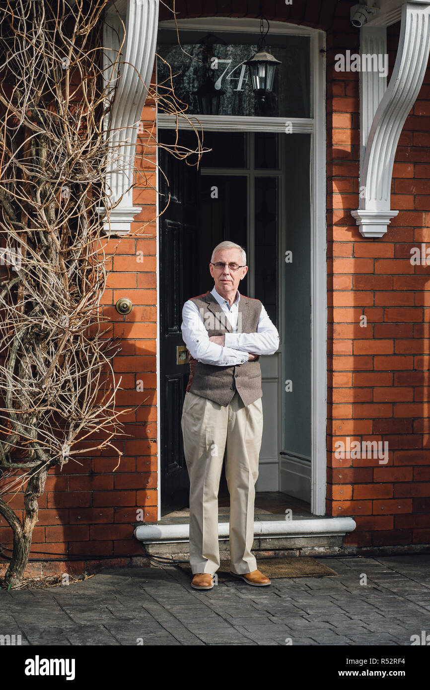Happy Senior Man Standing Outside The Front Door Of His Home He