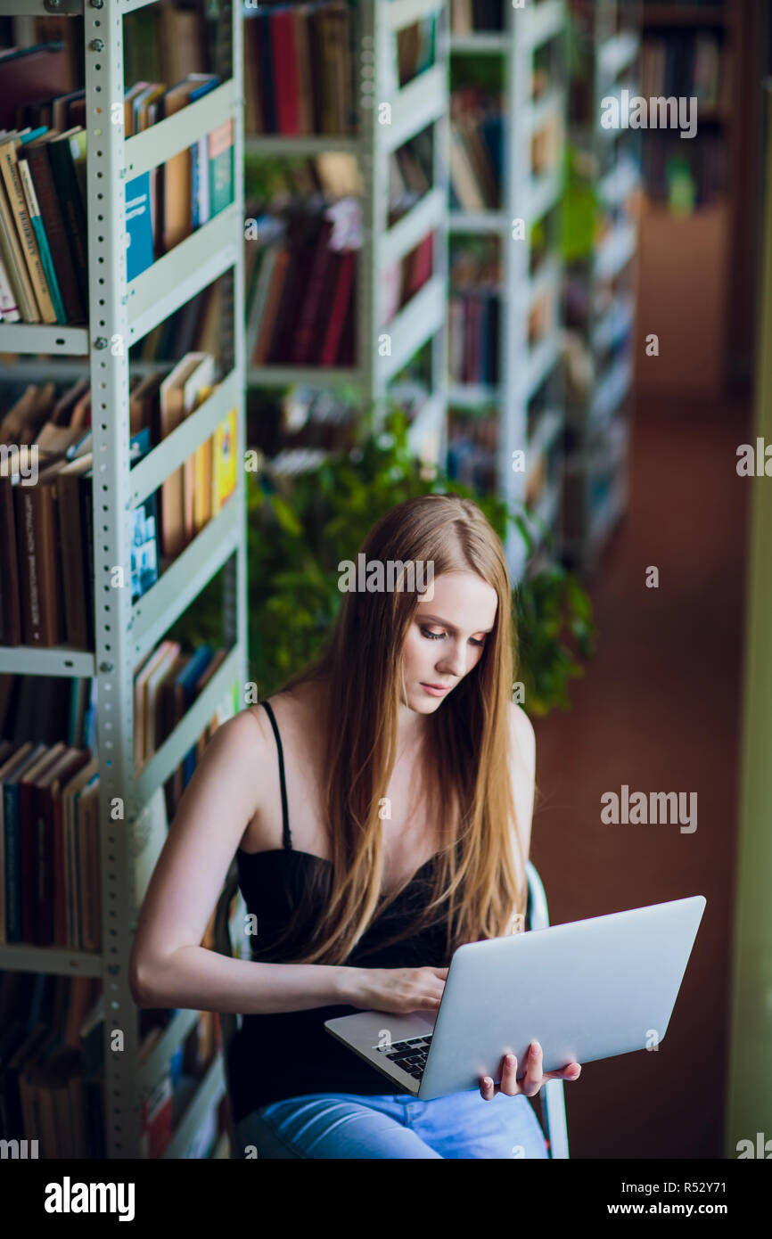 Happy smiling female student working with laptop in library Stock Photo ...