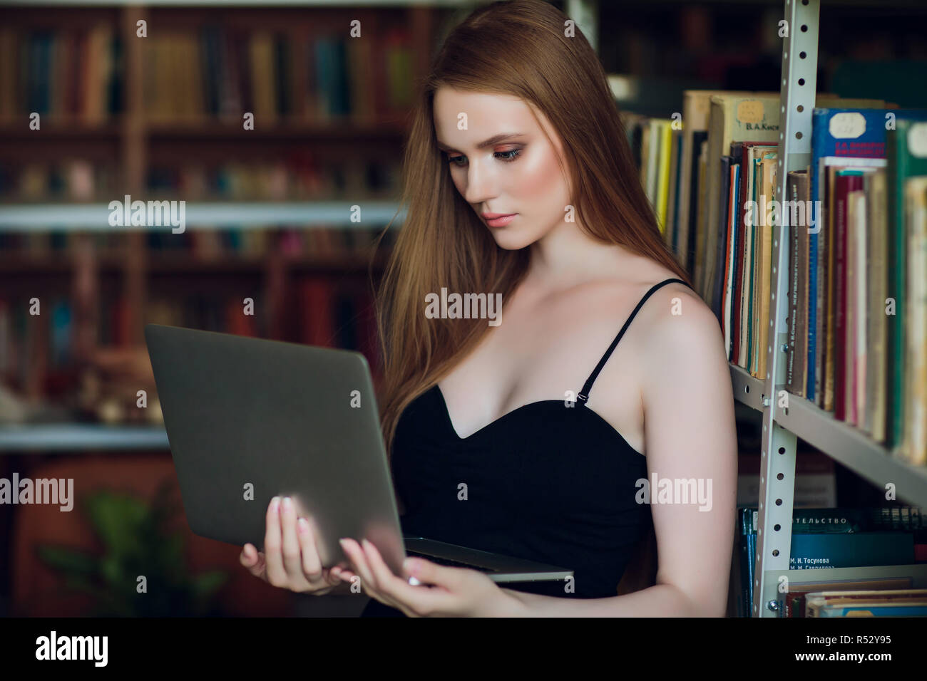 Happy smiling female student working with laptop in library Stock Photo ...
