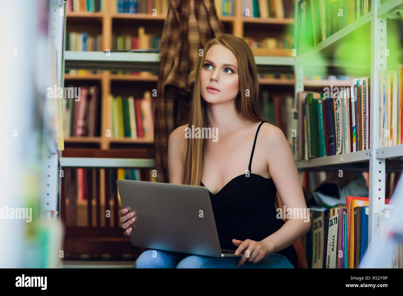 Happy smiling female student working with laptop in library Stock Photo ...
