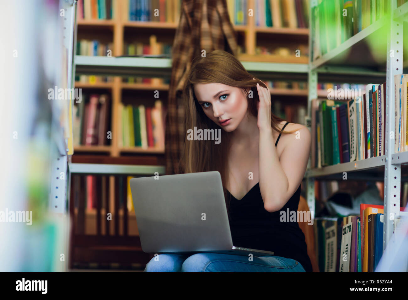 Happy smiling female student working with laptop in library Stock Photo ...