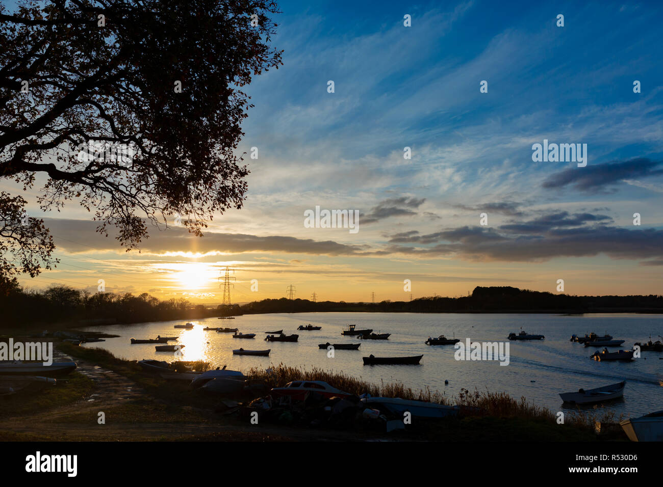 Landscape photograph of bay with many moored boats in sillhouette with sunset in background. Stock Photo