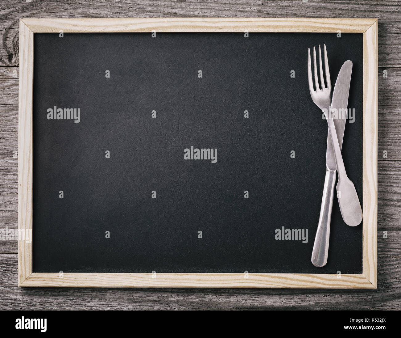 Empty menu blackboard with knife and fork on wooden background. Food background Stock Photo