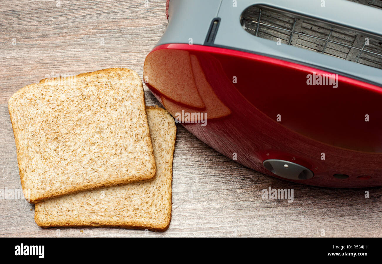 Modern toaster with toasted sliced  bread on wooden background. Kitchen equipment.Top view Stock Photo