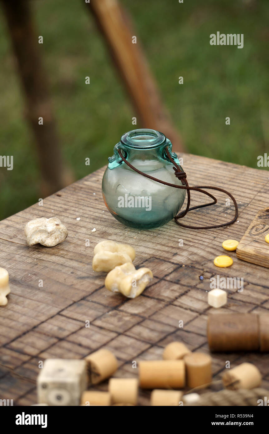 A small glass jar with a leather cord, on a wooden game board. Stock Photo