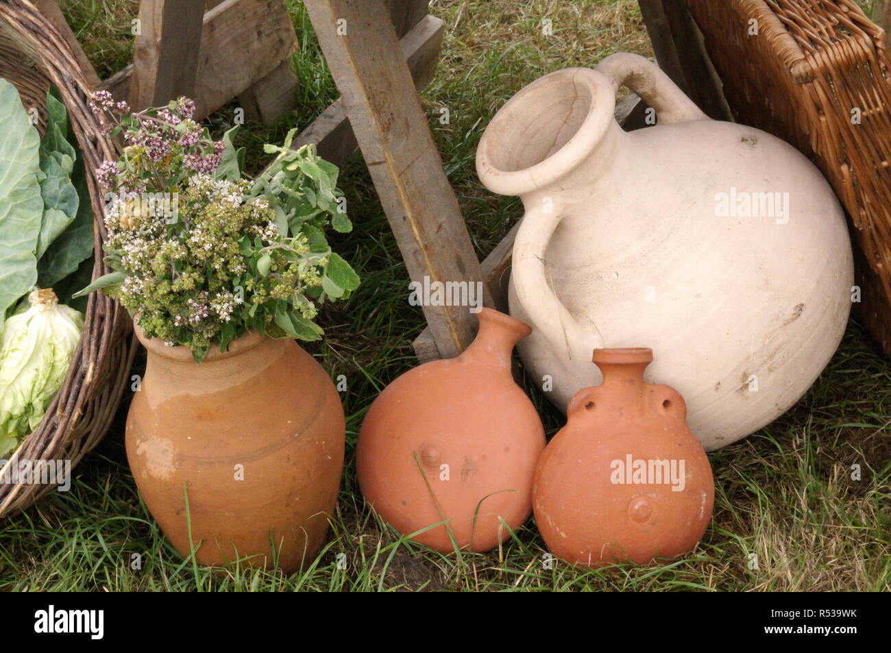 Roman pottery flasks and jugs, one with a bunch of herbs stuffed into it. Stock Photo