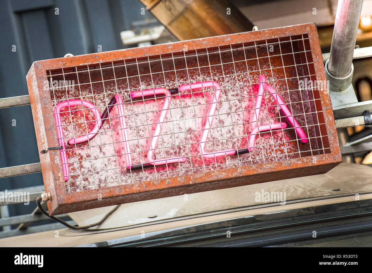 pink neon pizza sign inside a rusting metal cage Stock Photo