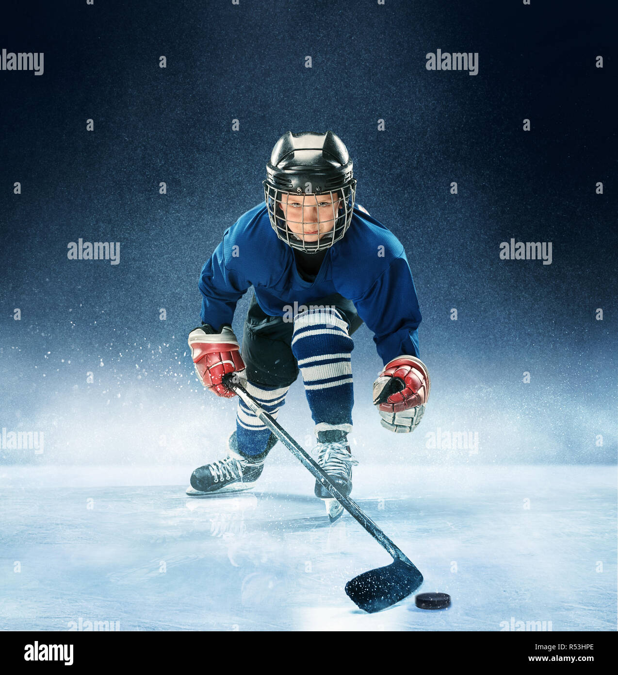 Little boy playing ice hockey at arena. A hockey player in uniform with